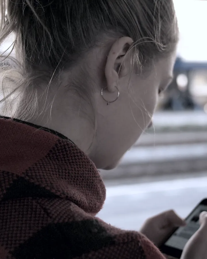 A young woman looking at her phone on a city street