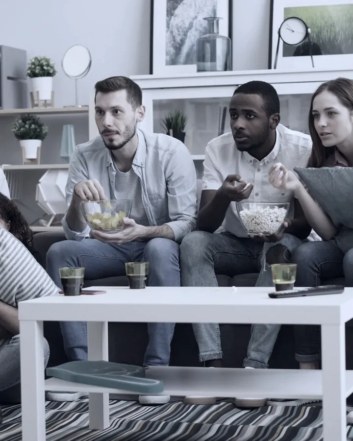 Friends watching television together in a living room