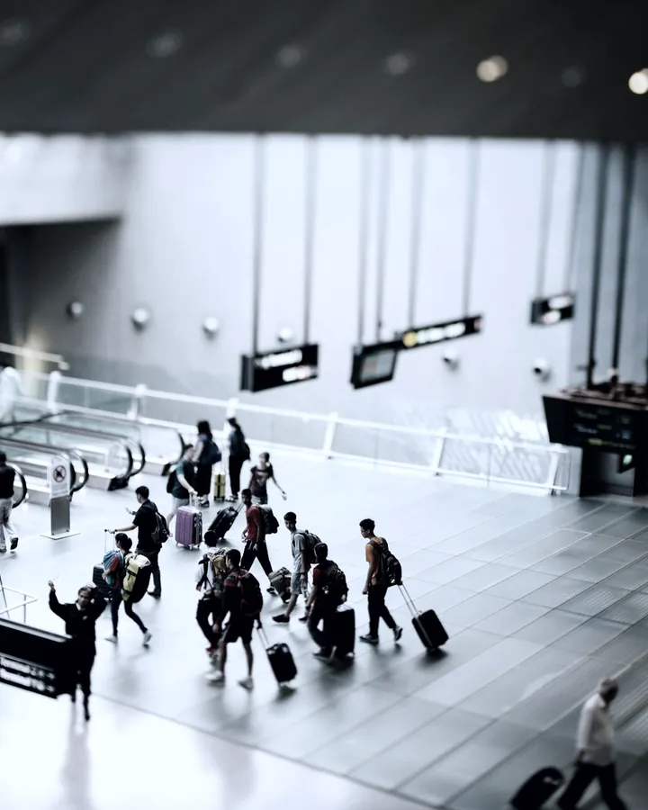 Travellers walking through an airport terminal with luggage